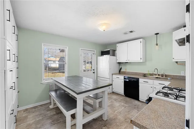 a kitchen with granite countertop a stove a sink dishwasher and a refrigerator with wooden floor