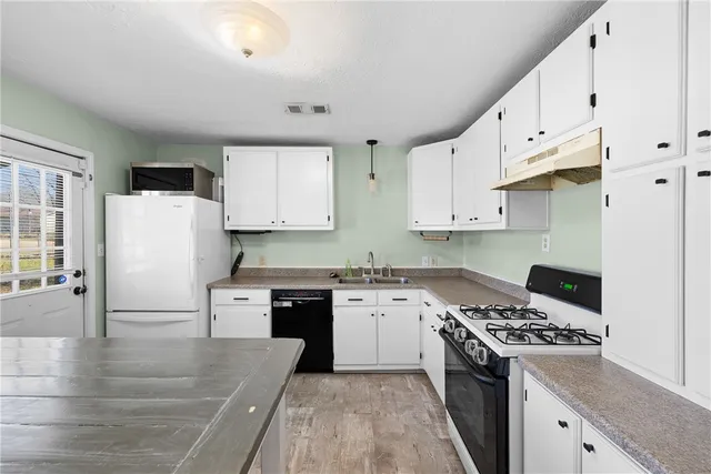 a kitchen with granite countertop a sink a stove a refrigerator and white cabinets