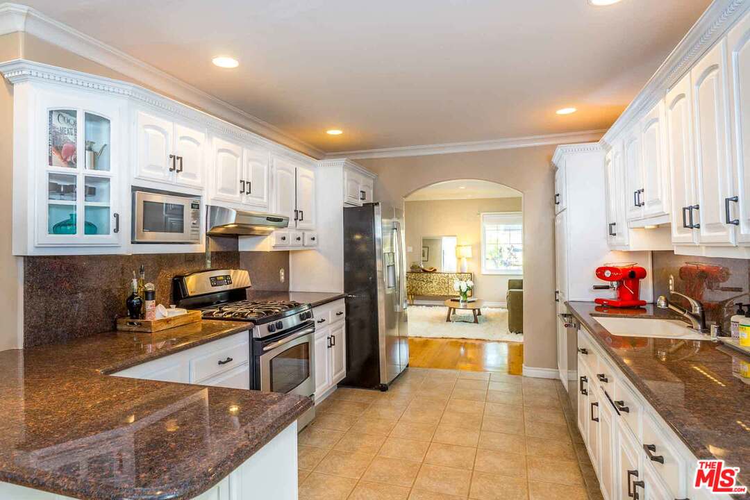 7418 Midfield Avenue Los Angeles, CA 90045 - Photo 13 of 28 a kitchen with stainless steel appliances granite countertop a stove top oven a sink dishwasher a refrigerator and white cabinets with wooden floor