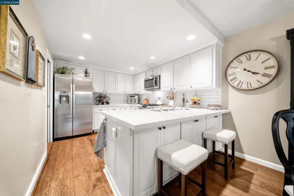 a kitchen with cabinets a center island stainless steel appliances with a dining table and chairs