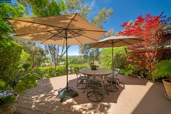 a view of a patio with table and chairs potted plants with wooden floor and fence