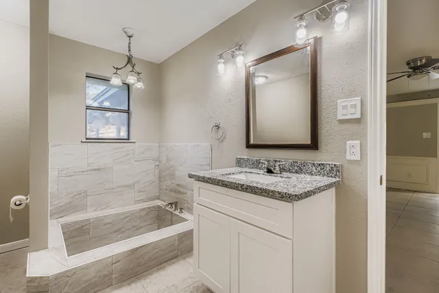 a bathroom with a granite countertop sink a mirror a bathtub and shower