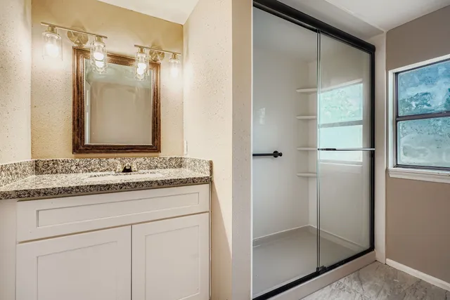 a bathroom with a shower sink and mirror