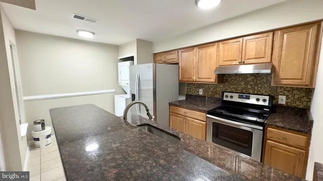 a kitchen with stainless steel appliances granite countertop a stove a sink and a refrigerator