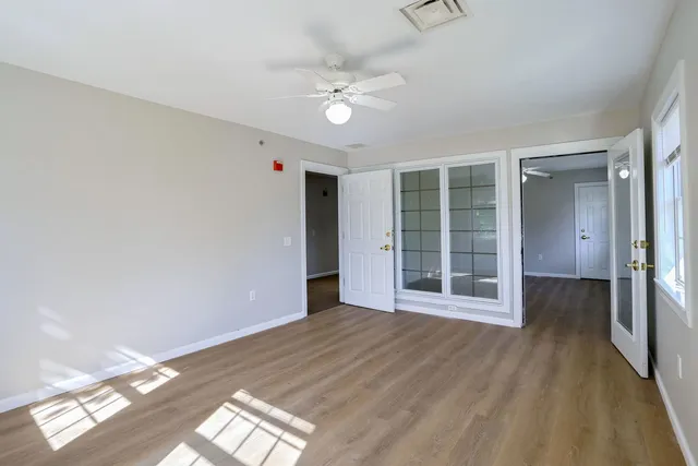 a view of an empty room with wooden floor and a window