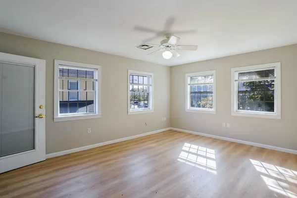 an empty room with wooden floor and fan