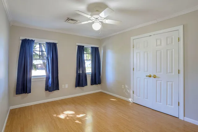 a view of an empty room with a window and wooden floor
