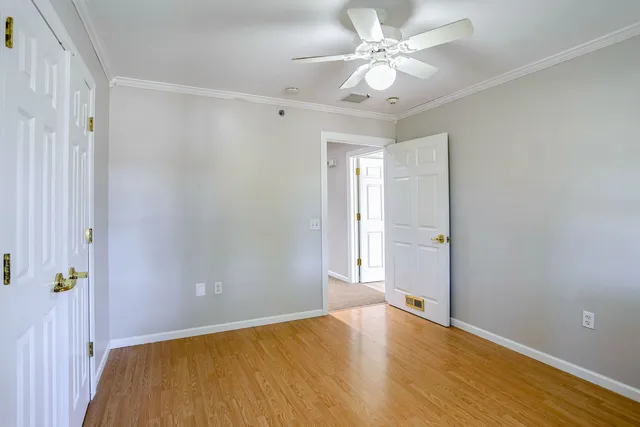an empty room with wooden floor and fan