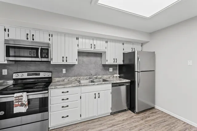 a kitchen with stainless steel appliances granite countertop a refrigerator stove and white cabinets