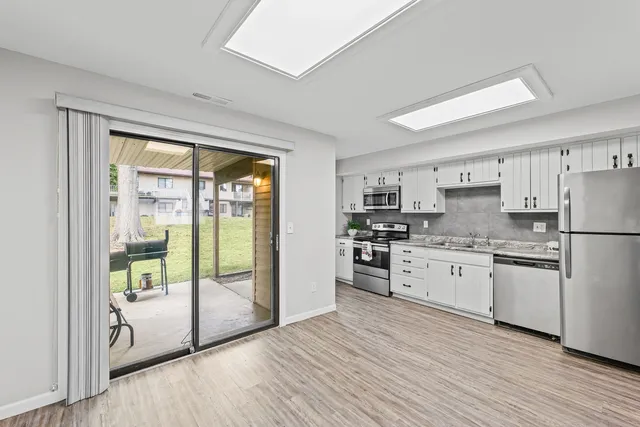 a kitchen with stainless steel appliances granite countertop a refrigerator a stove a sink and a large window