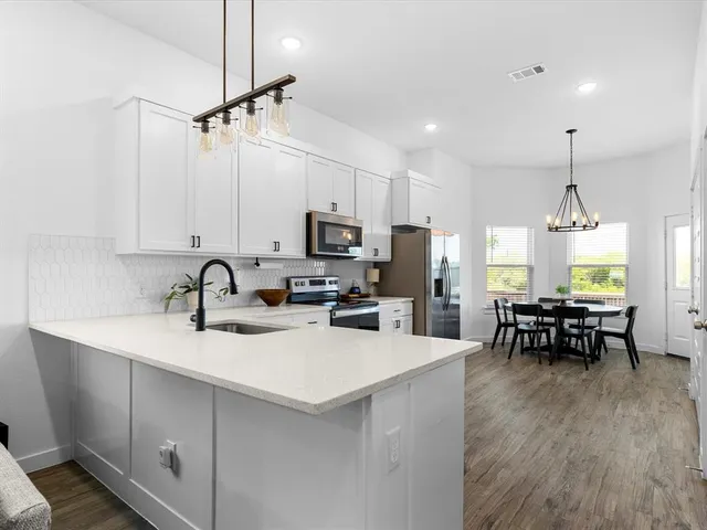 a kitchen with kitchen island granite countertop a sink a counter space appliances and cabinets