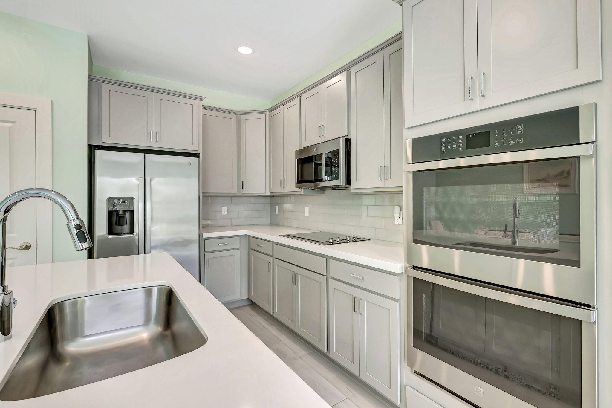1404 Gopher Terrace Stuart, FL 34994 - Photo 10 of 52 a kitchen with stainless steel appliances granite countertop a sink a microwave a refrigerator and white cabinets