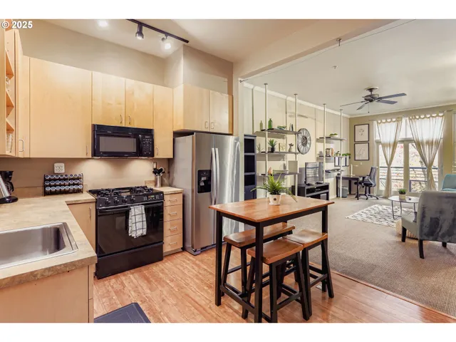 a kitchen with stainless steel appliances granite countertop a stove a refrigerator a kitchen island a table and chairs