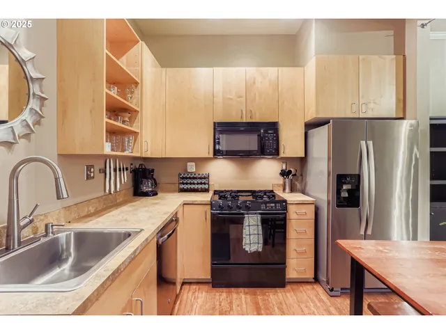 a kitchen with stainless steel appliances granite countertop a sink stove refrigerator and a large window