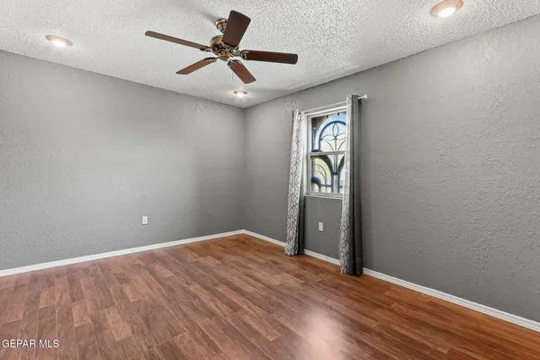 a view of an empty room with window and wooden floor