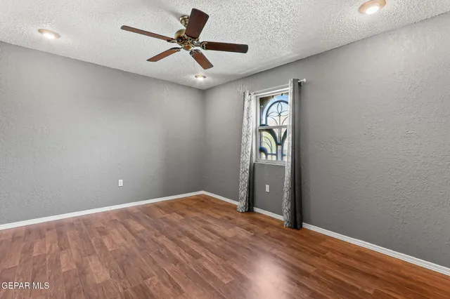 a view of an empty room with window and wooden floor