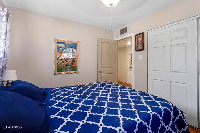 a bedroom with a large bed and a lamp on dresser