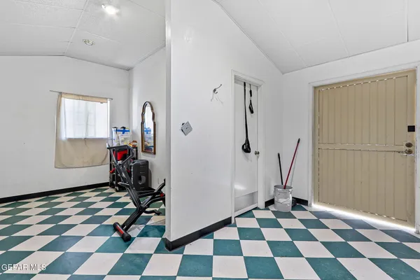 a room with a black white checkered floor with a gaming machine and a rug