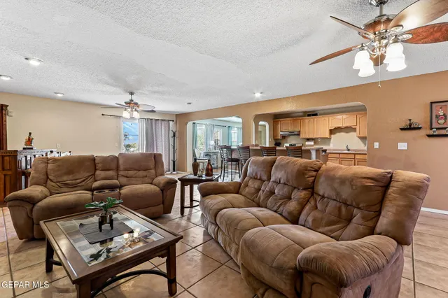 a living room with furniture a ceiling fan a lamp and a window