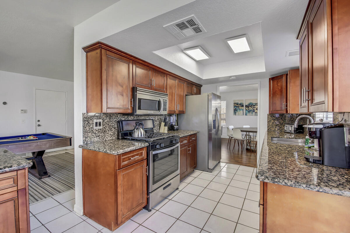 45640 Cimarron Road Indio, CA 92201 - Photo 9 of 25 a kitchen with stainless steel appliances granite countertop a stove top oven a sink dishwasher a dining table and chairs with wooden floor