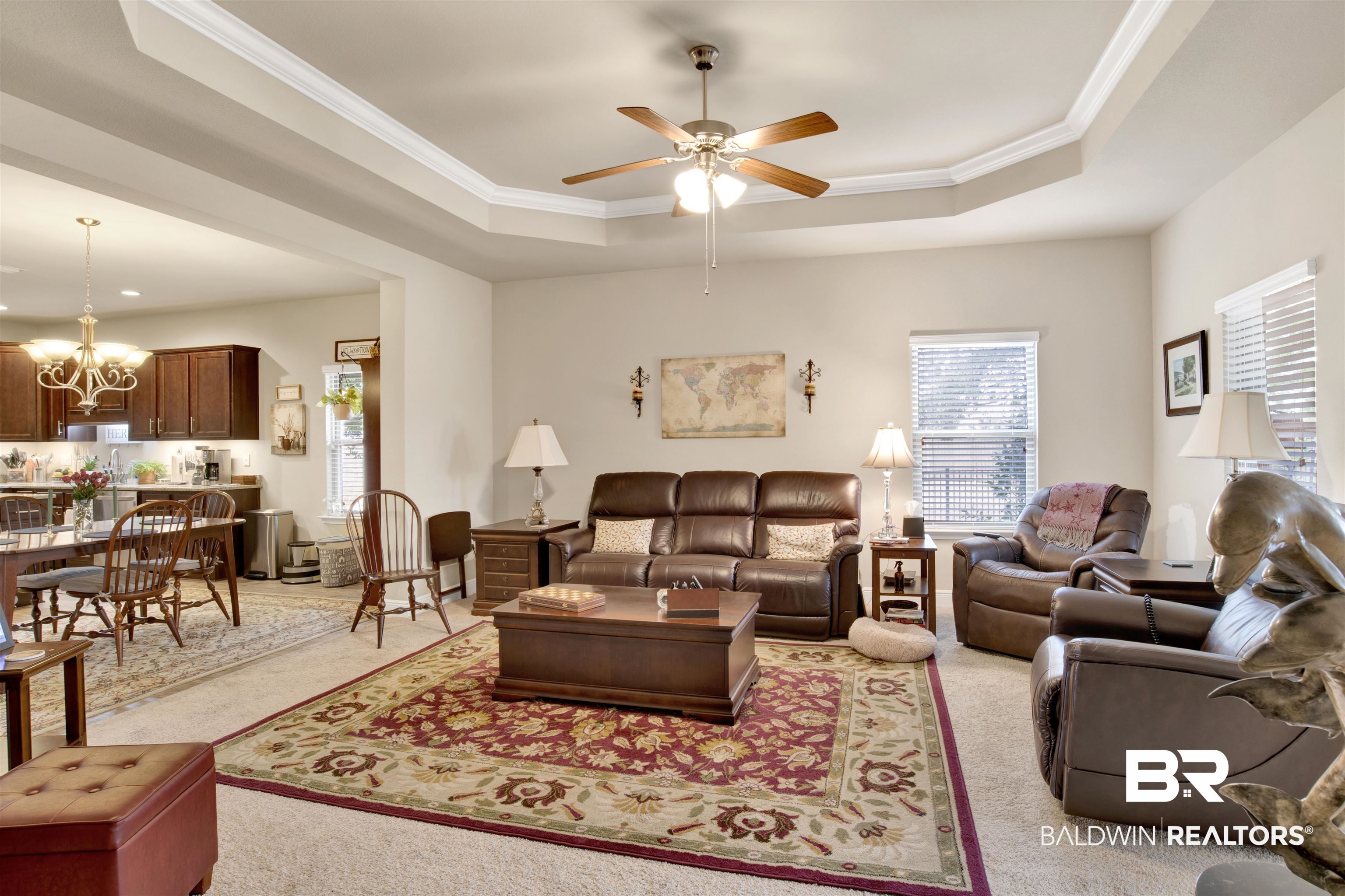 1476 Surrey Loop Foley, AL 36535 - Photo 18 of 31 Carpeted living room featuring crown molding, ceiling fan with notable chandelier, and a tray ceiling