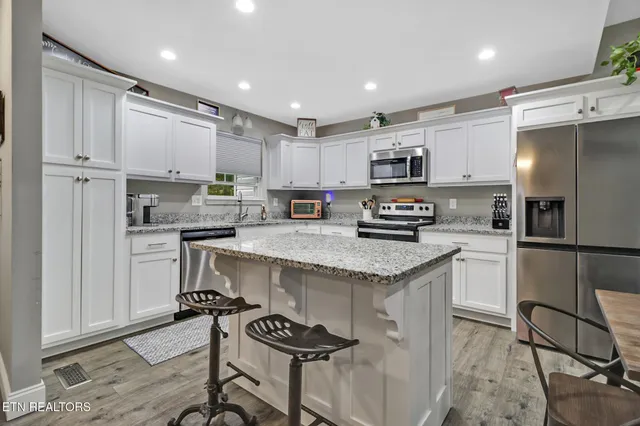 a kitchen with granite countertop a refrigerator stove microwave and cabinets