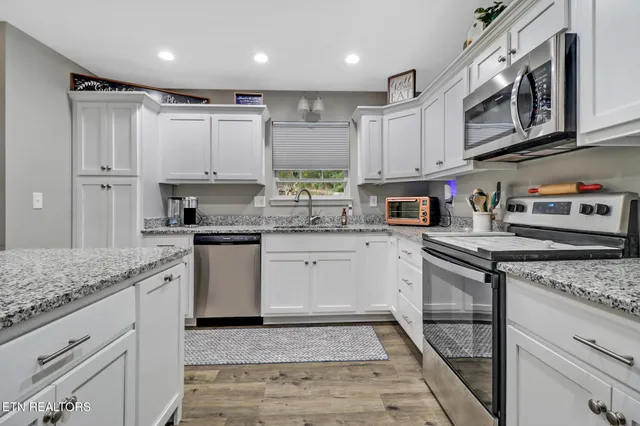 a kitchen with stainless steel appliances granite countertop a sink a stove and cabinets