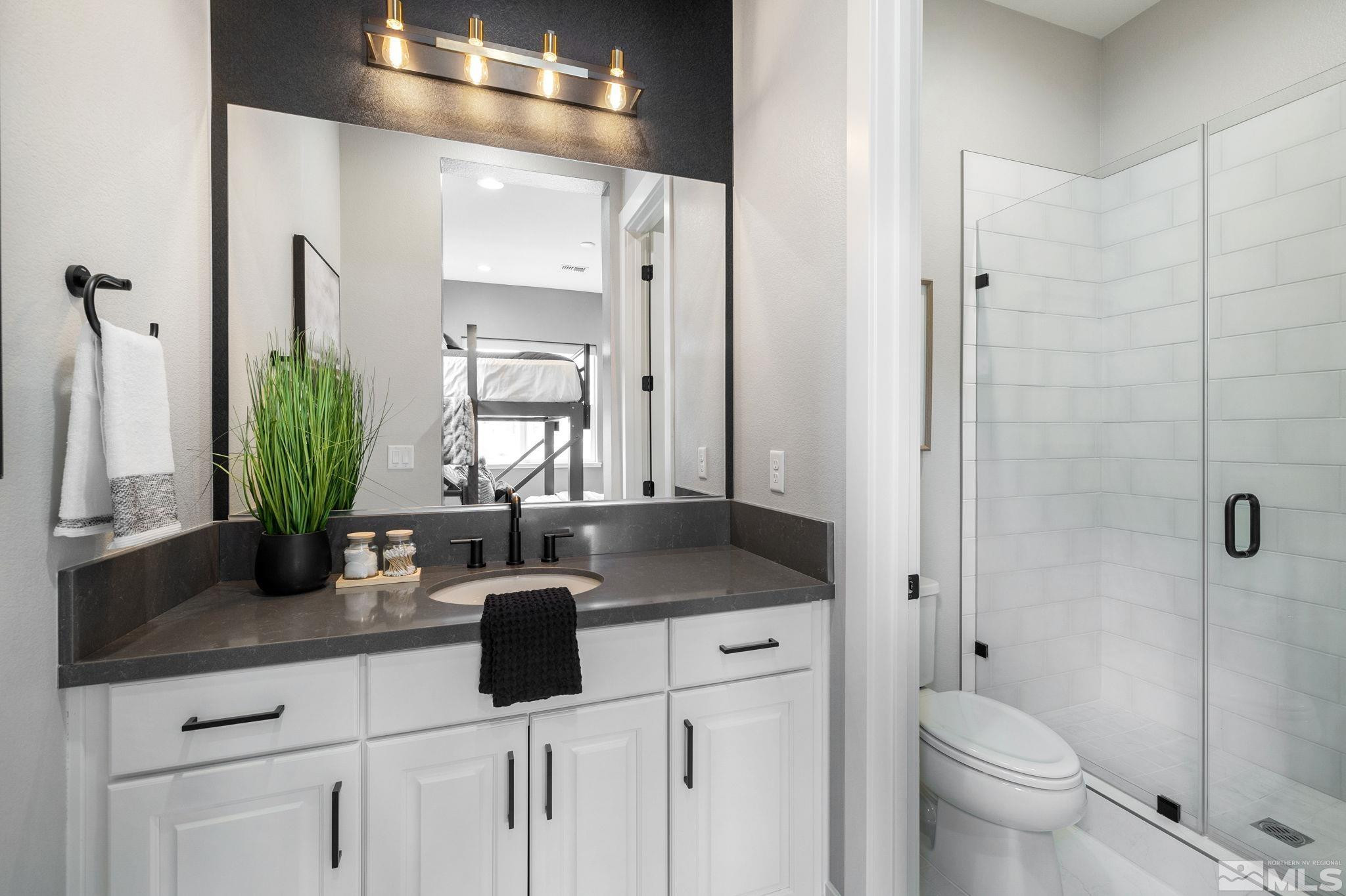 2913 Ruby Desert Drive Reno, NV 89521 - Photo 26 of 39 a bathroom with a granite countertop sink a toilet a mirror and shower