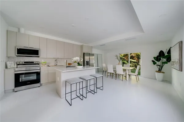 a kitchen with stainless steel appliances a table chairs refrigerator and cabinets