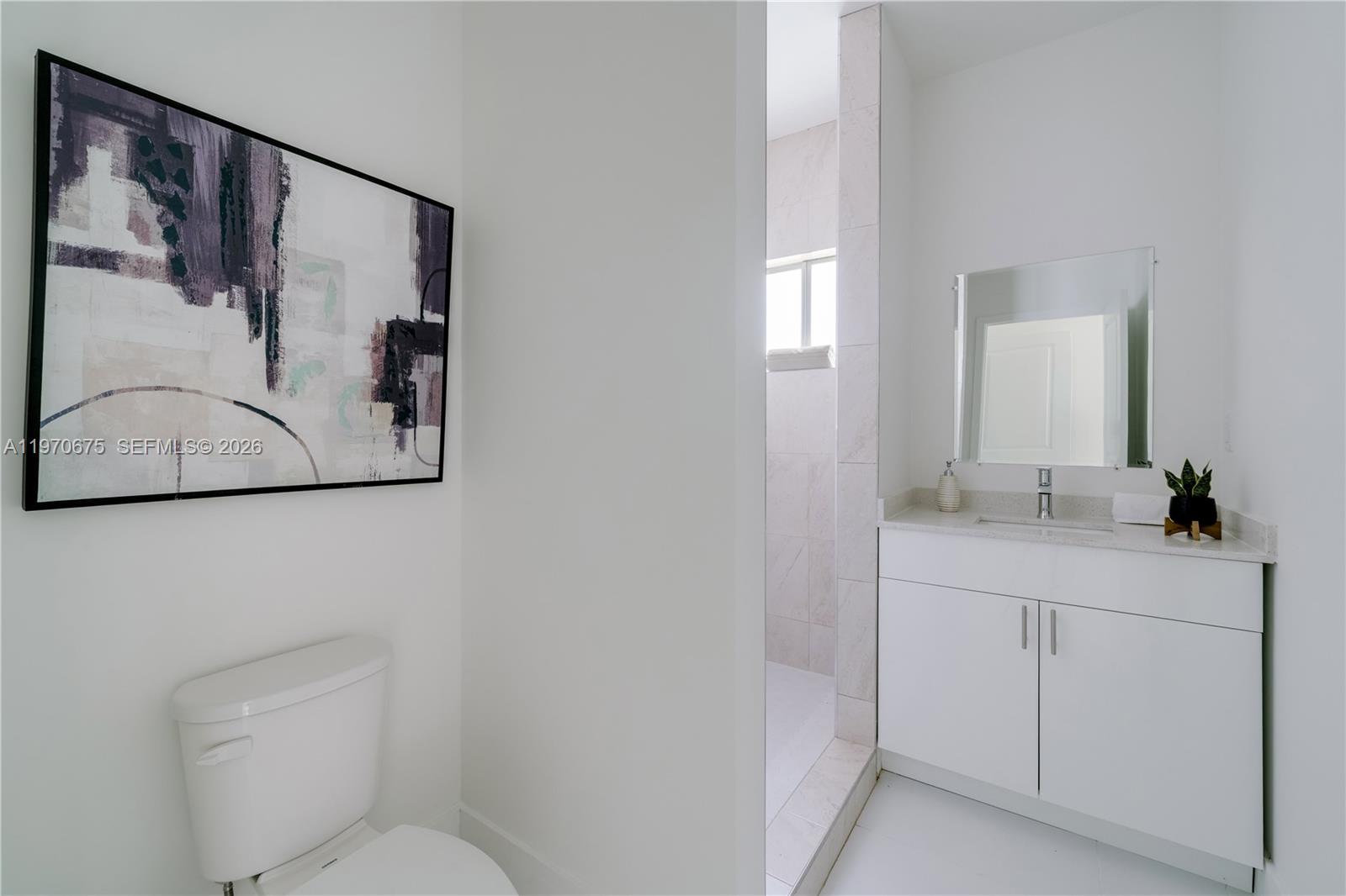 4789 Northwest 1st Street Miami, FL 33126 - Photo 20 of 28 a bathroom with a toilet sink vanity and mirror