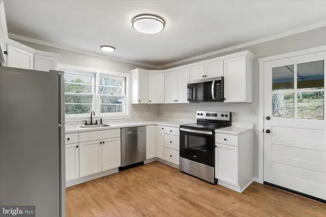 a kitchen with granite countertop white cabinets and black stainless steel appliances
