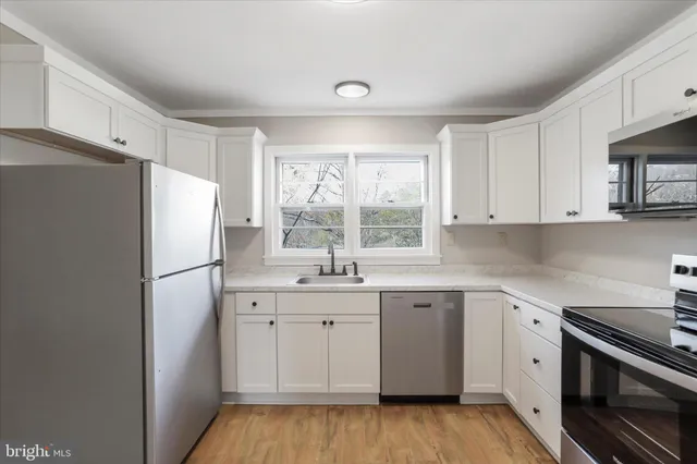 a kitchen with a sink a refrigerator a window and cabinets