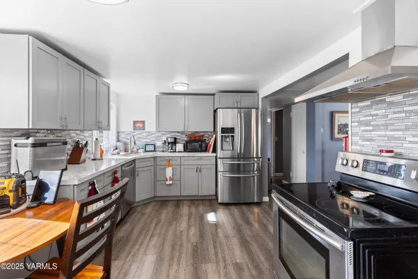 a kitchen with a refrigerator a sink dishwasher a stove and a dining table with wooden floor