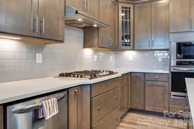 a kitchen with stainless steel appliances a sink a stove and cabinets