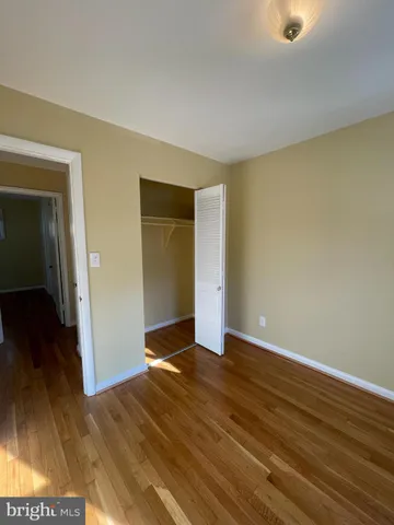 a view of an empty room with wooden floor and closet