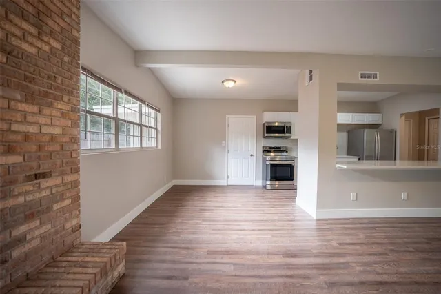 a view of a kitchen with wooden floor and a fireplace