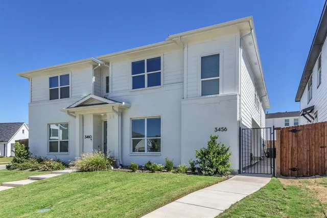 a view of a white house next to a yard