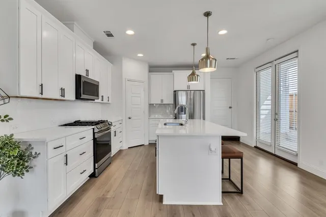 a large kitchen with stainless steel appliances a lot of counter space and wooden floor