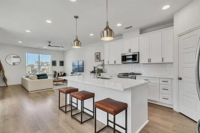 a kitchen with kitchen island granite countertop a stove a sink a dining table and chairs with wooden floor