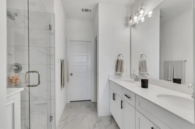 a bathroom with a double vanity sink a shower and a mirror