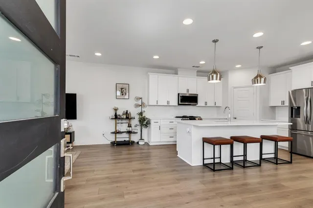 a kitchen with stainless steel appliances kitchen island granite countertop a stove top oven a sink a refrigerator and white cabinets