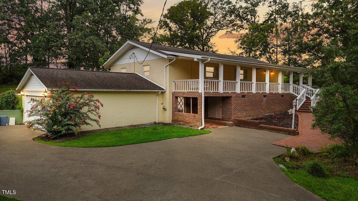 a view of a house with a yard and a large tree