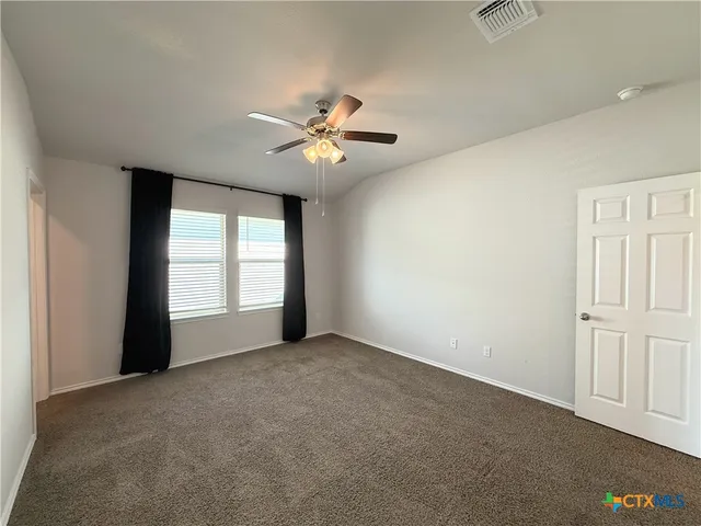 an empty room with chandelier fan and windows