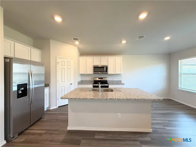 a view of kitchen with stainless steel appliances granite countertop a stove a refrigerator and a sink