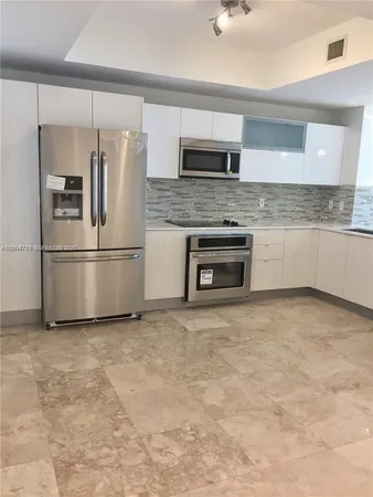 a kitchen with granite countertop a refrigerator and a stove top oven
