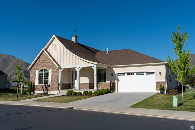1222 West 190th Street North Mapleton, UT 84664 - Photo 42 of 46 Stone and stucco facade featuring an arched window, covered porch entry, two-car garage, and a gable roof with a weather vane