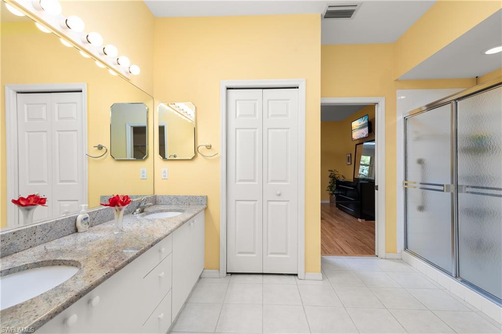 455 Crossfield Circle, Unit 71 Naples, FL 34104 - Photo 16 of 29 a spacious bathroom with a granite countertop sink mirror and shower