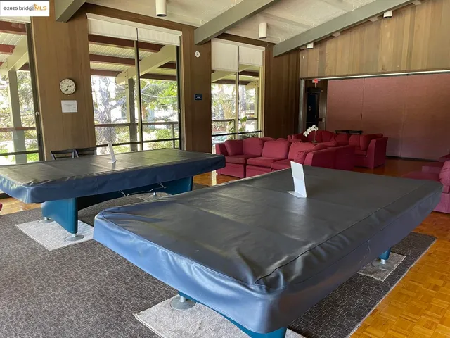 a living room with furniture pool table and large windows
