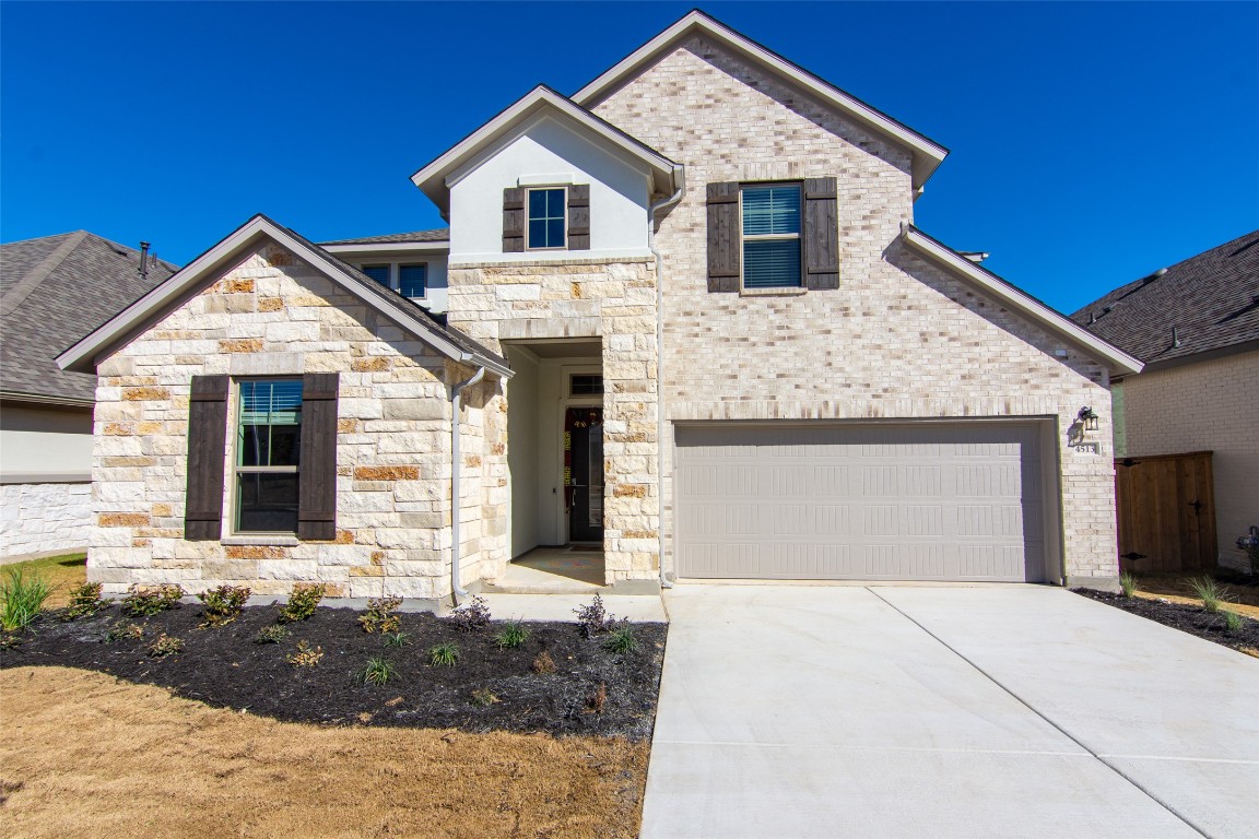 French country inspired facade featuring driveway and stone siding