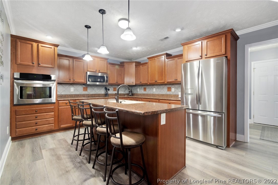 274 Deaton Road Raeford, NC 28376 - Photo 19 of 49 a kitchen with kitchen island granite countertop wooden floors and white cabinets